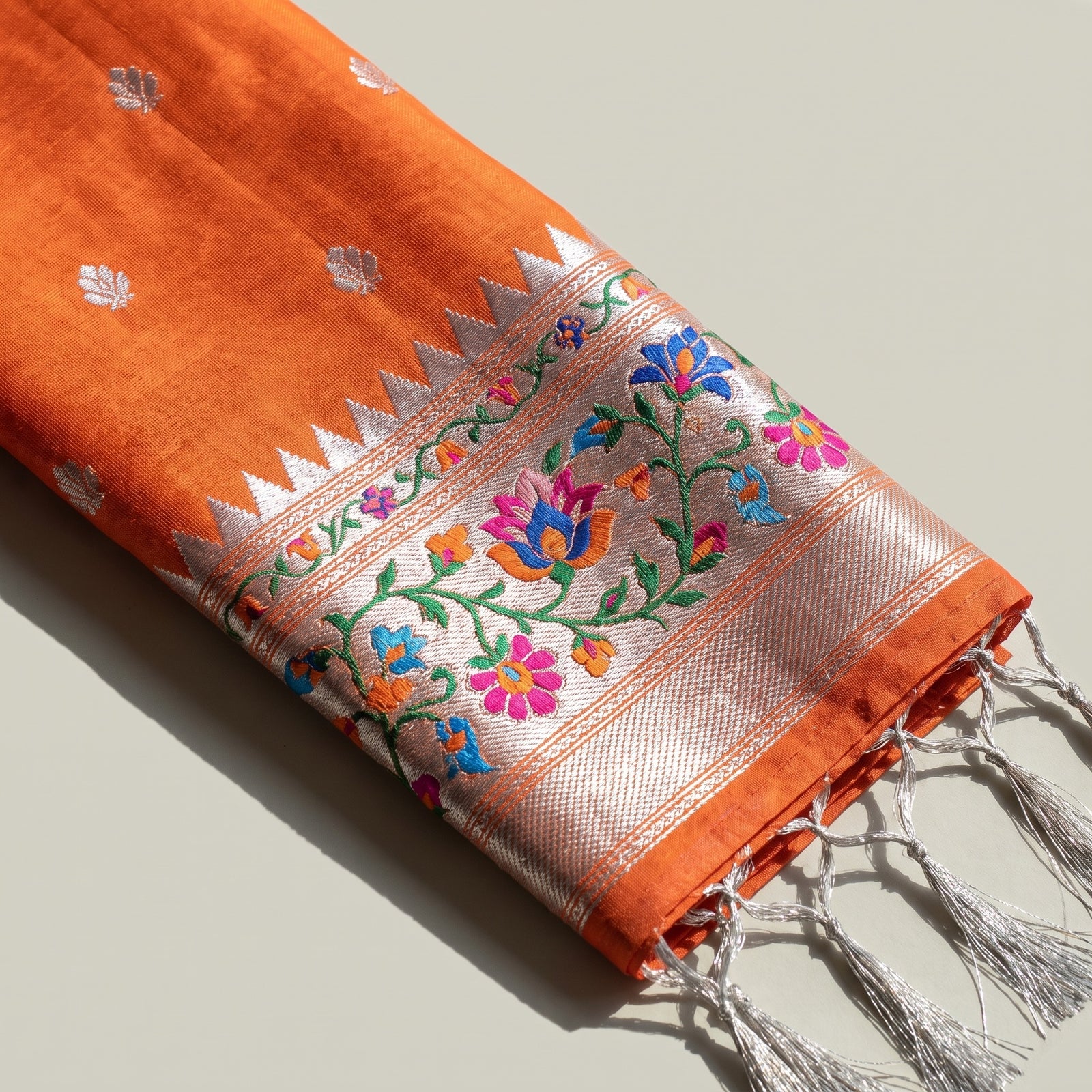 Folded orange pure kora saree showing the scut border and body motifs
