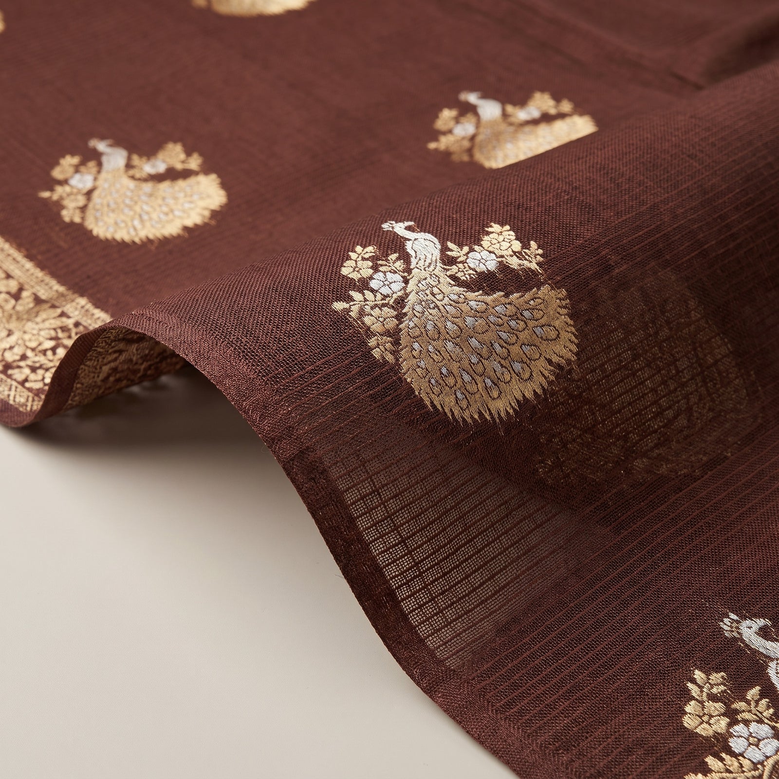 Neatly folded chocolate brown Pure Manipuri Kota saree highlighting zari border