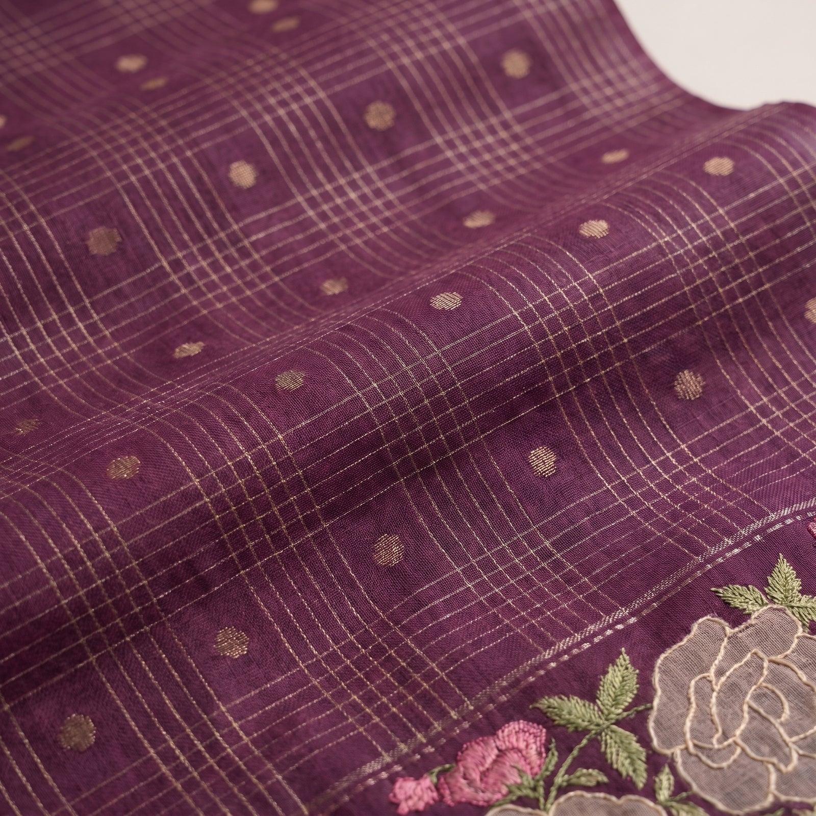 Close-up of embroidered rose border along the lower edge of violet saree